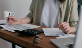 Someone does accounting with a laptop and paperwork.
