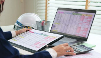 Person cross-checking laptop with clipboard