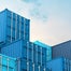 Blue containers stacked under blue sky
