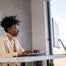 Woman at desk using computer next to window