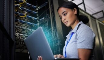 Woman on laptop next to electronics panel
