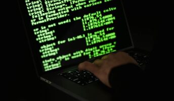 Someone types code on a computer in the dark