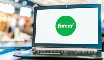 Fiverr logo on open laptop with busy background