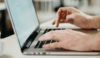 Hands typing on a laptop
