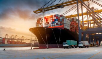Shipping containers on a truck near a ship