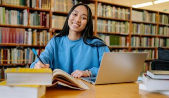 Woman with books and laptop in a library