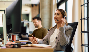 A woman sits at a desk using a conference call service.
